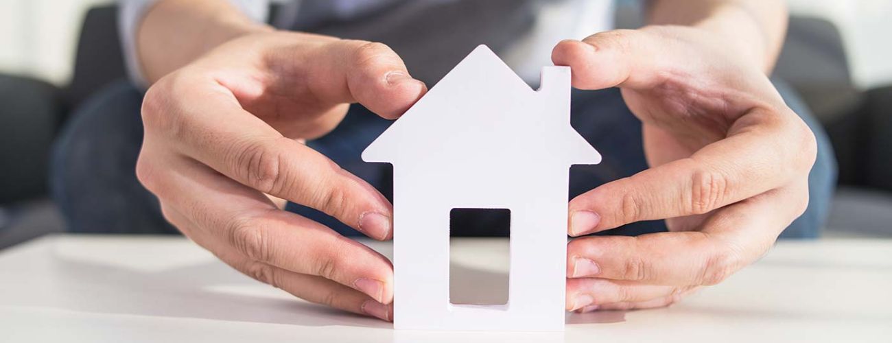 Photo zoom maquette maison d&eacute;coup&eacute; avec deux mains la tenant sur fond clair