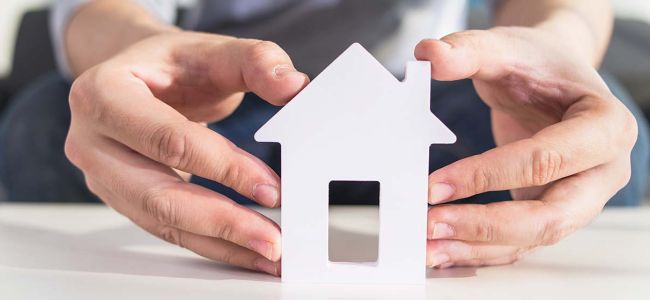 Photo zoom maquette maison découpé avec deux mains la tenant sur fond clair