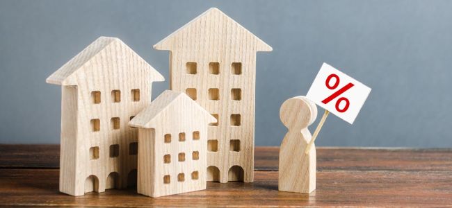 3 petites maisons en bois et un petit homme sur un bureau en bois